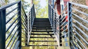 Un escalier en métal, doté de rampes également en métal, mène à un bâtiment.
