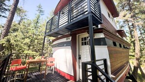 Une cabine avec un balcon, une terrasse avec des chaises et une porte.