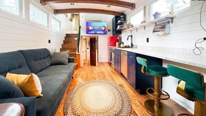 Un espace de vie compact comprenant un canapé, un coin bar et une cuisine.