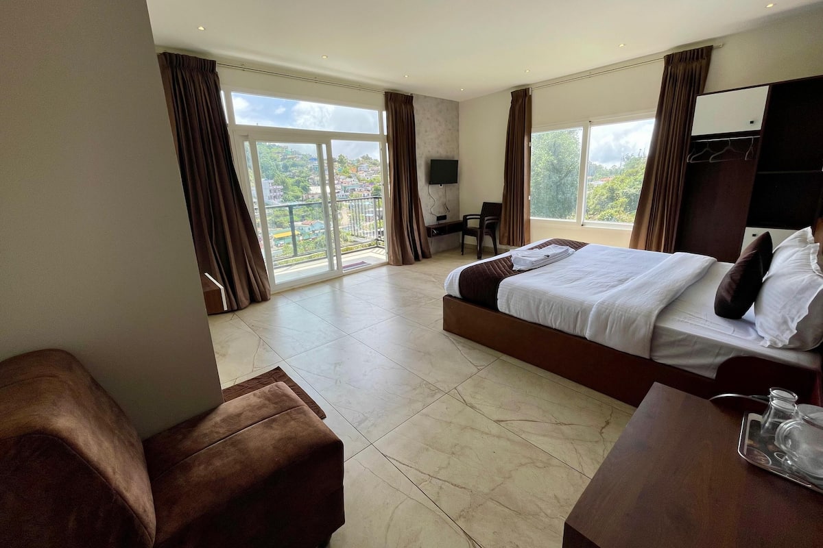 A hotel room with a large bed, a desk, a chair, and a TV.