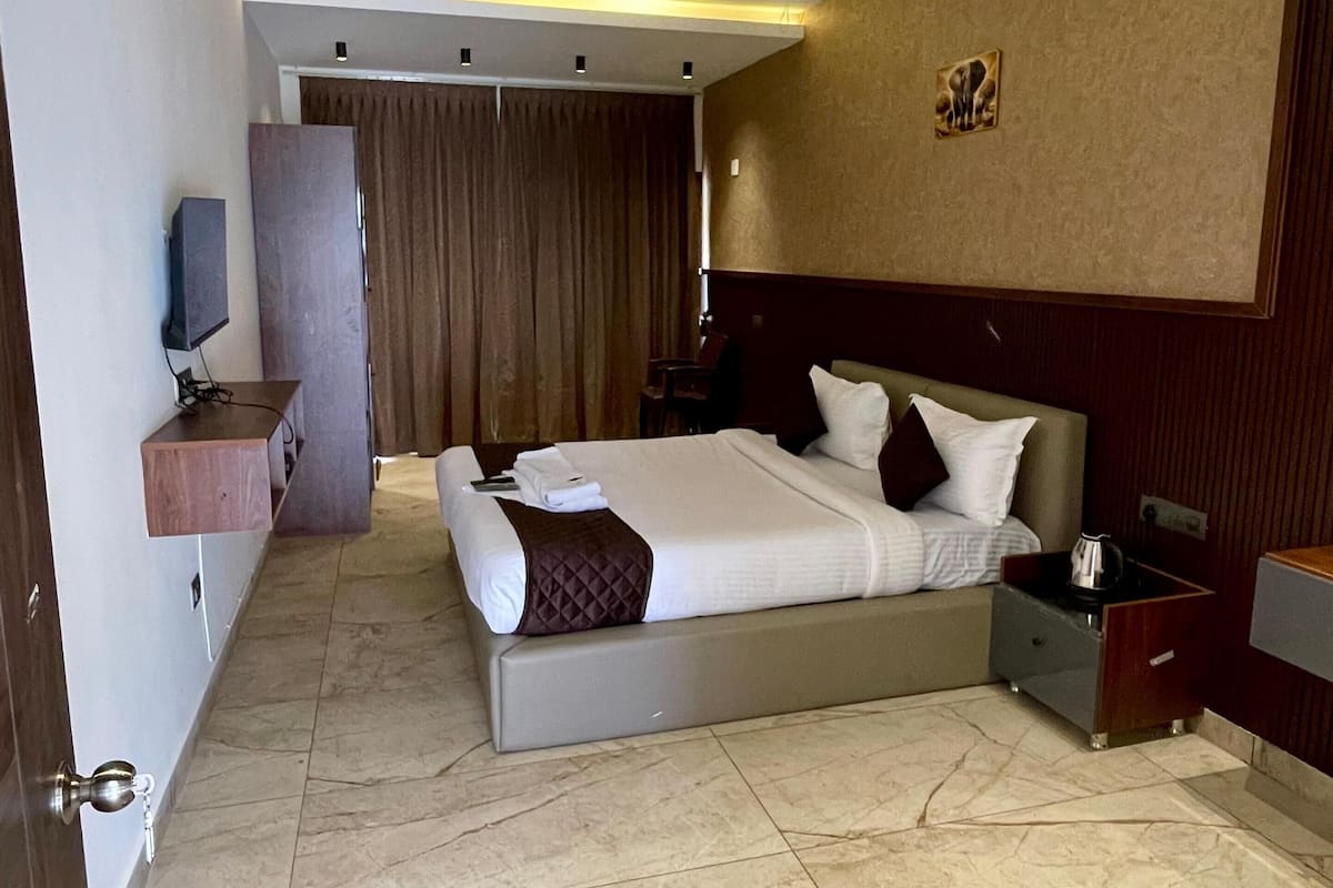 A hotel room with a bed, bedside tables, a TV, and a bathroom with a shower and toilet.