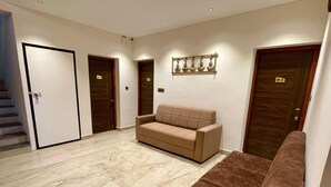 A hotel lobby with a beige sofa, a brown sofa, and a marble floor. There are doors labeled B-1, B-2, and B-3. - The Lake House (Kodaikanal)