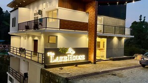A two-story building with a sign reading "The Lake House." It features a balcony on the upper floor and a ground-level entrance. - The Lake House (Kodaikanal)