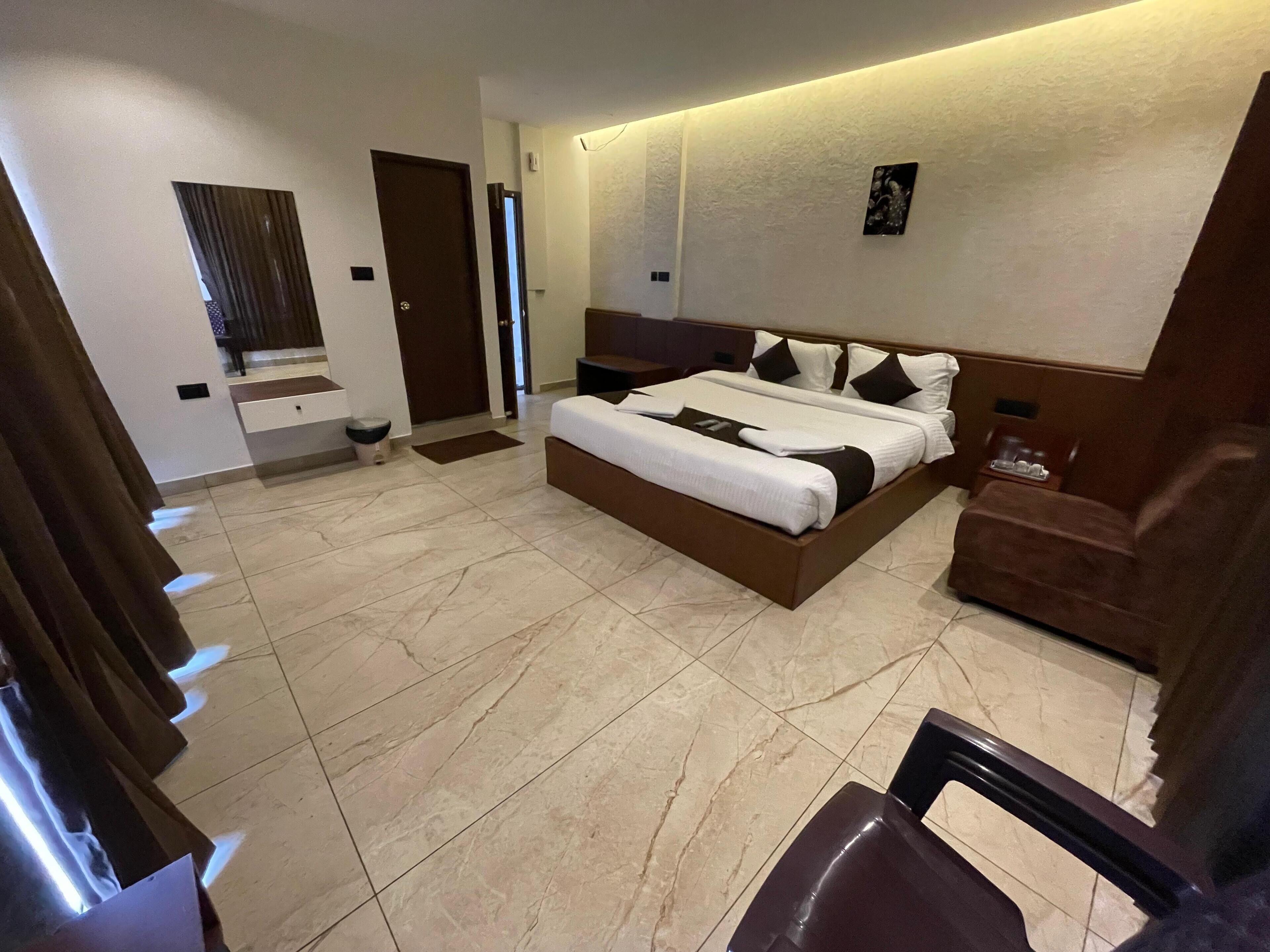 A modern hotel room with a large bed, a seating area with a sofa, and a small table.