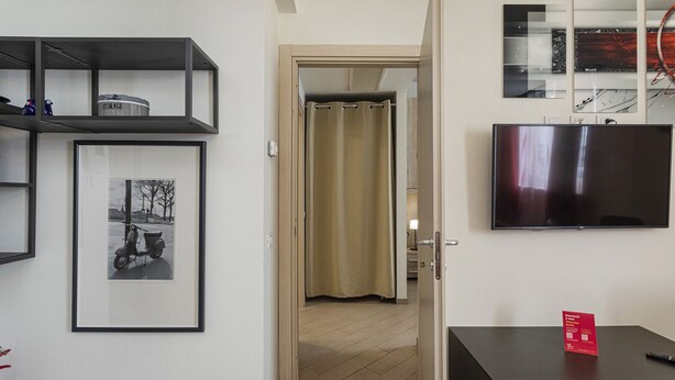 Un salon moderne avec un téléviseur à écran plat, une photographie encadrée accrochée au mur et une petite table sur laquelle est posée une carte rouge.