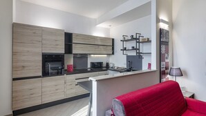 Une cuisine moderne avec des meubles en bois, un four encastré et un four à micro-ondes. On y trouve également un coin repas avec une table et des chaises.