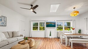 A modern living room with a sofa, coffee table, and dining area. - koolkondo 2597 Halalu Guest house (Koloa)