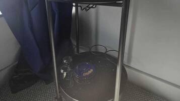 A small kitchenette with a coffee maker, a kettle, and a pot on a metal cart.