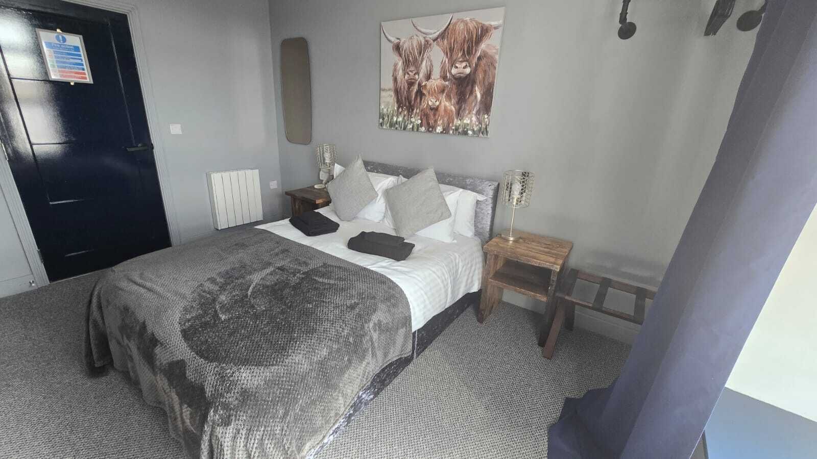 A bedroom with a bed, pillows, a bedside table with a lamp, a radiator, and a door.