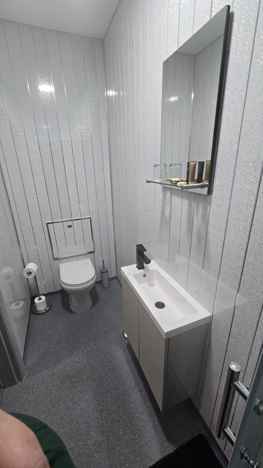 Een badkamer met toilet, wastafel en spiegel.