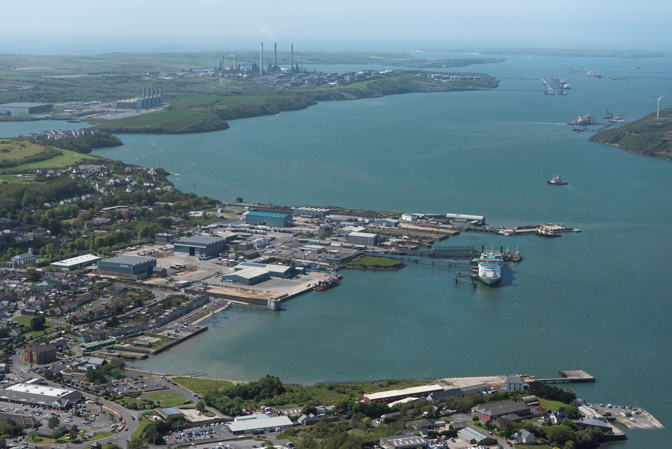 An industrial area with a large body of water, several buildings, and a bridge.