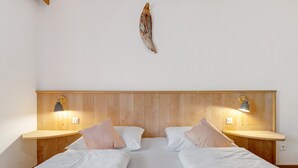 Ein Doppelbett mit weißer Bettwäsche, zwei Nachttische mit Lampen und ein hölzernes Kopfteil.