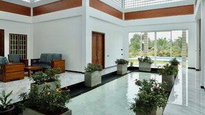 Un vaste espace intérieur doté d’une piscine, de coins salon et de plantes en pot.