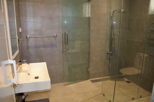 Une salle de bain moderne avec une douche à parois de verre, un lavabo blanc et une porte en verre.