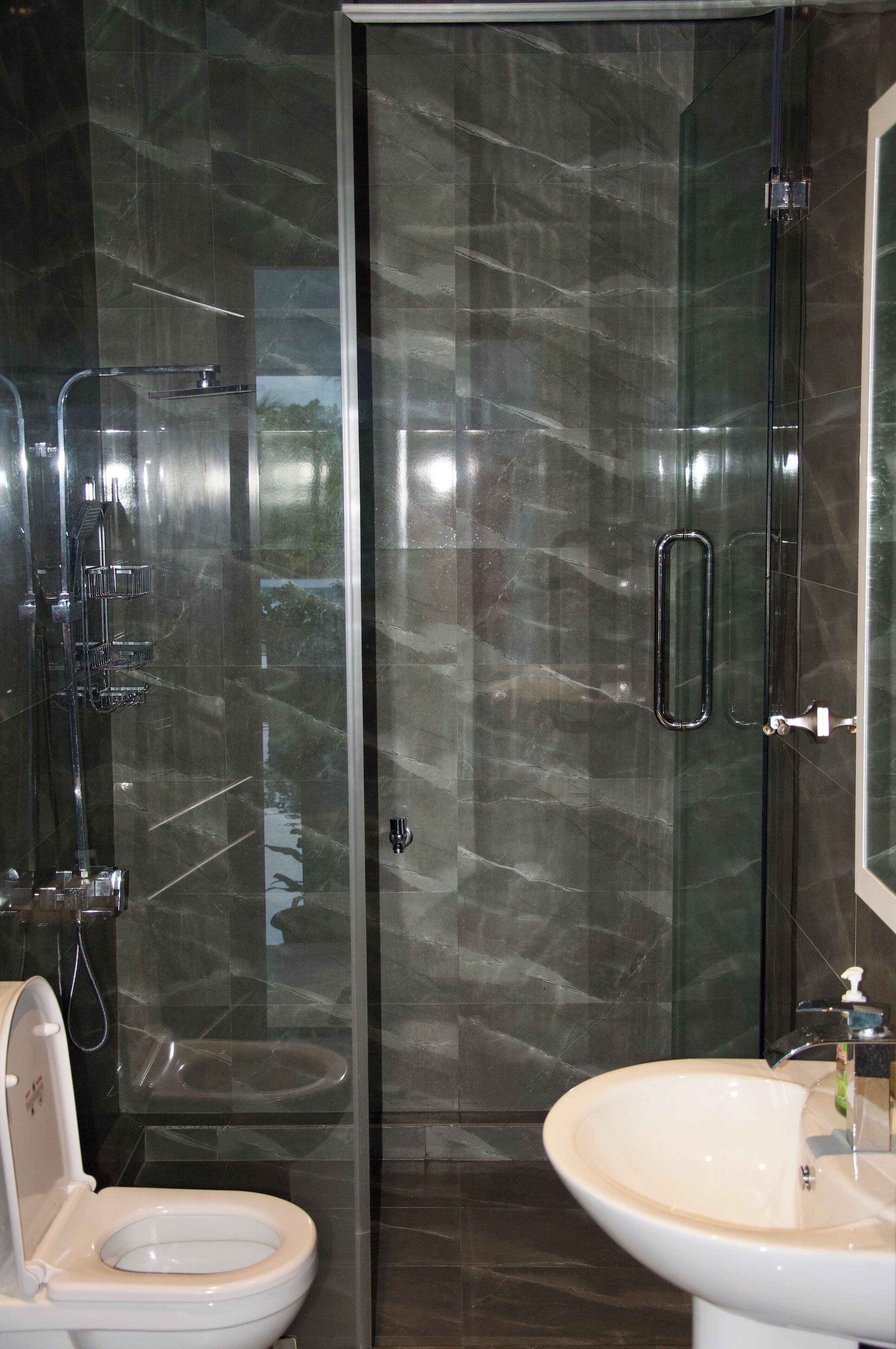 A modern bathroom with a glass-enclosed shower, a white toilet, and a beige sink.