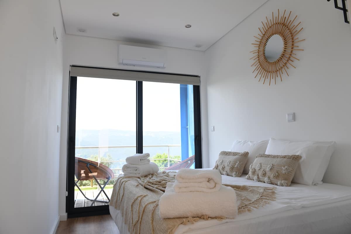 Un dormitorio con cama, ventana grande y balcón.