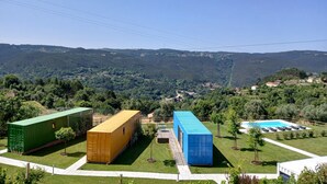Ein Wohngebiet mit Pool, grünen und gelben Versandcontainern und Blick auf die umliegenden Hügel.