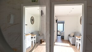 Ein modernes Interieur mit einem Flur, der in einen Wohnbereich führt. Weiße Wände, Holzboden und ein Sofa mit einem kleinen Tisch.