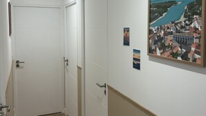 A hallway with white doors, a wooden floor, and a framed picture on the wall. - Bright house (Pornic)