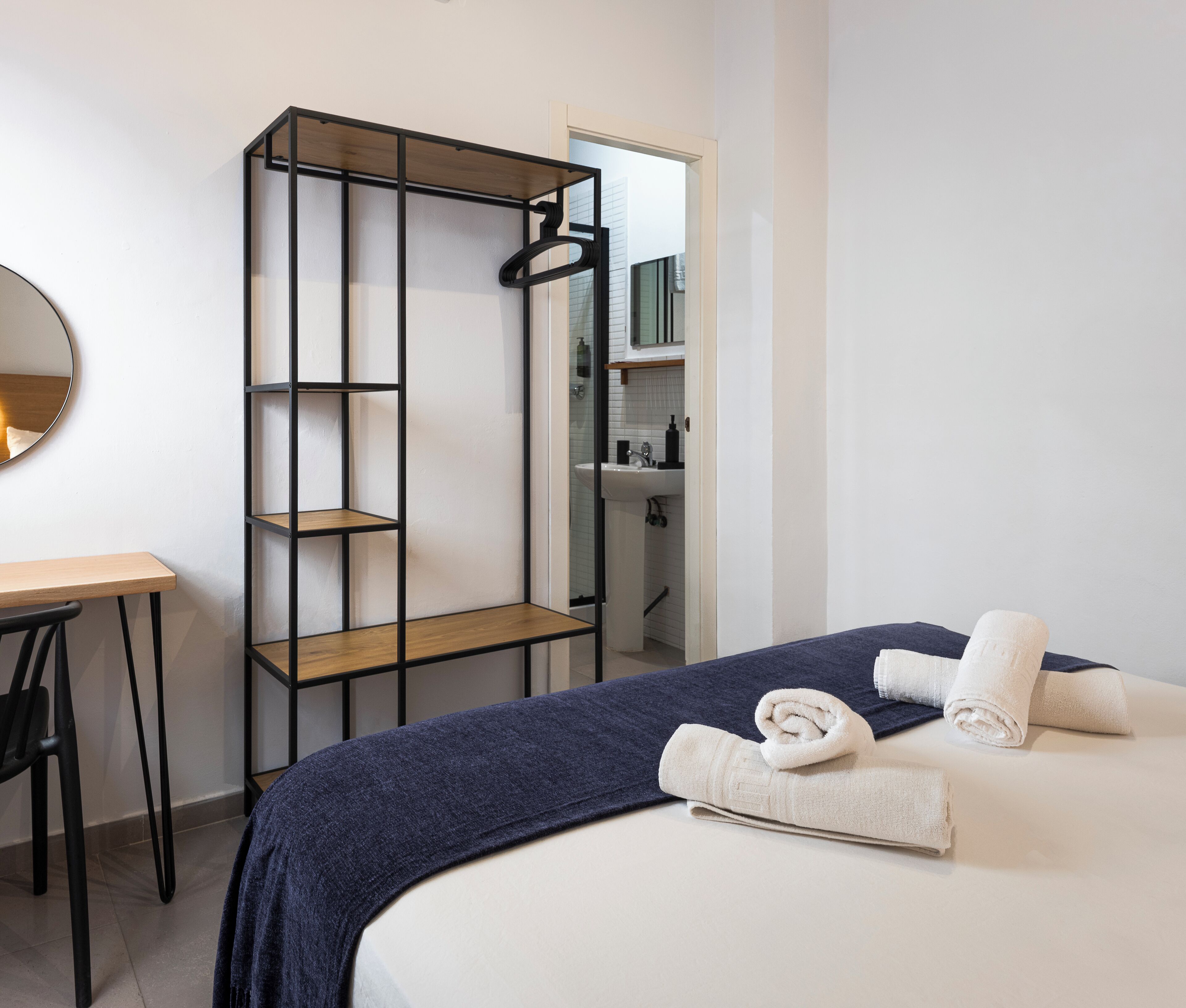 Une chambre d’hôtel avec un lit, un bureau, un miroir et une armoire.