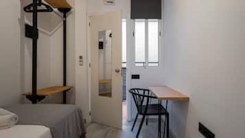 A compact room with a bed, a desk, and a chair.