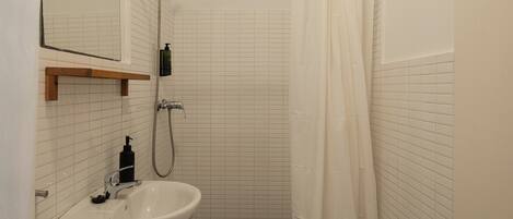 Un baño con lavamanos blanco, espejo y cortina de ducha.