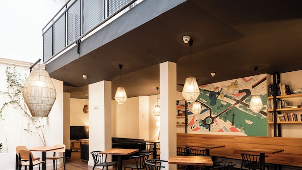 A modern interior with wooden flooring, multiple seating areas, and a large map mural on the wall. - La Central Sevilla (Seville)