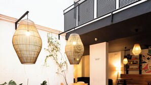 A modern interior with wooden tables and chairs, hanging wicker lamps, and a white brick wall. - La Central Sevilla (Seville)