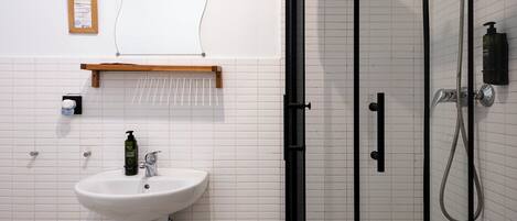 A bathroom with a white sink, a glass shower enclosure, and a tiled floor.
