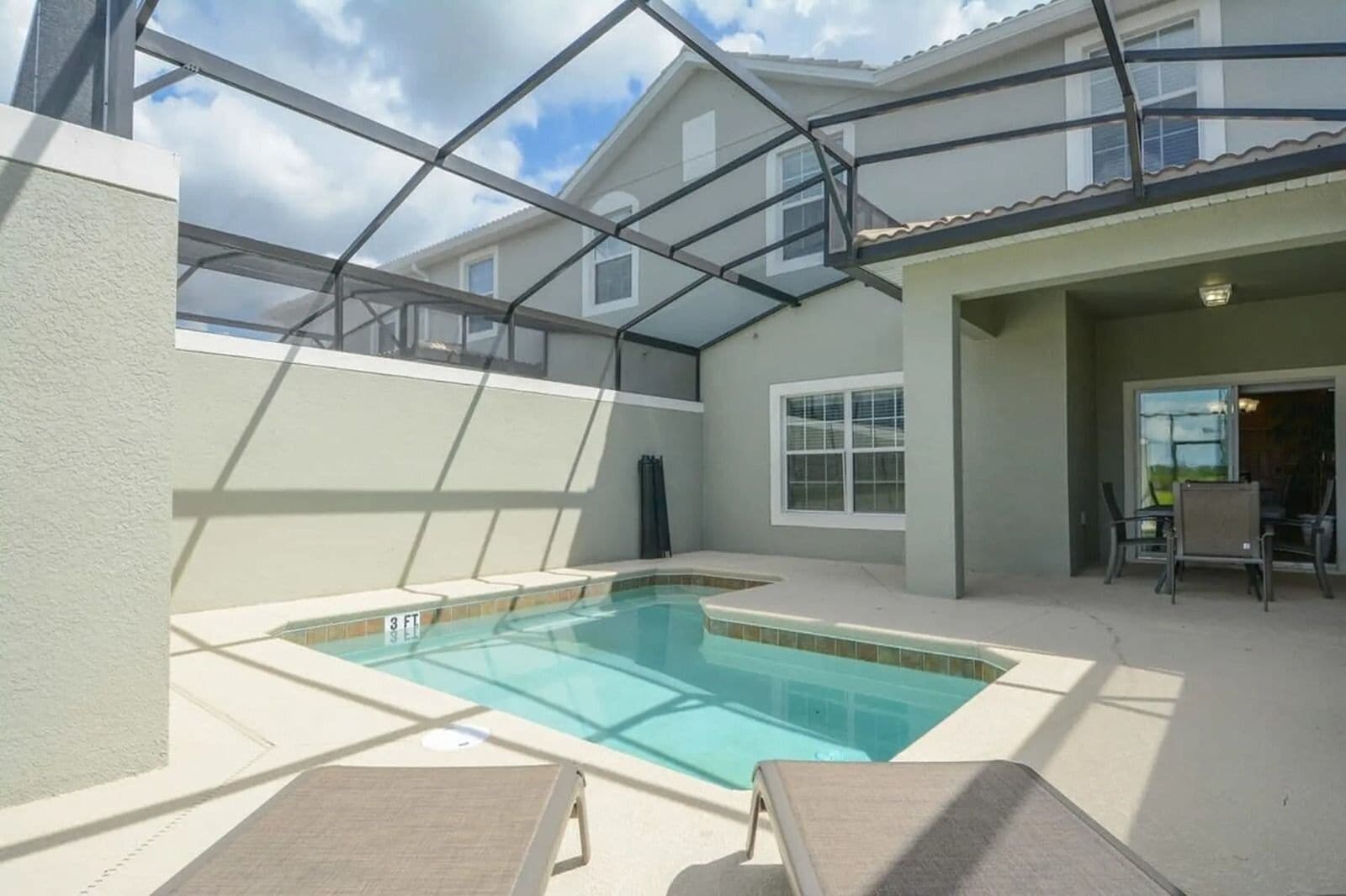 A backyard with a swimming pool, covered patio, and outdoor seating area.