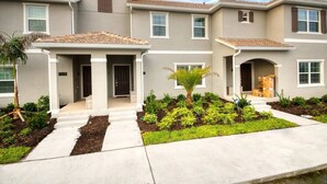 A multi-story residential building with a tiled roof, a covered front porch, and a landscaped front yard.