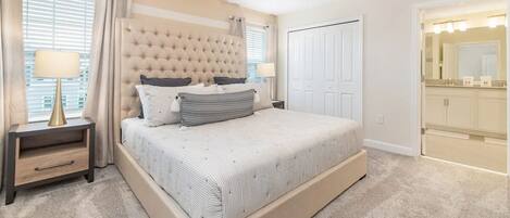 A bedroom with a large bed, bedside tables, a wardrobe, and a bathroom visible through an open door.