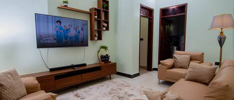 A living room with a TV, sofa, and a lamp.