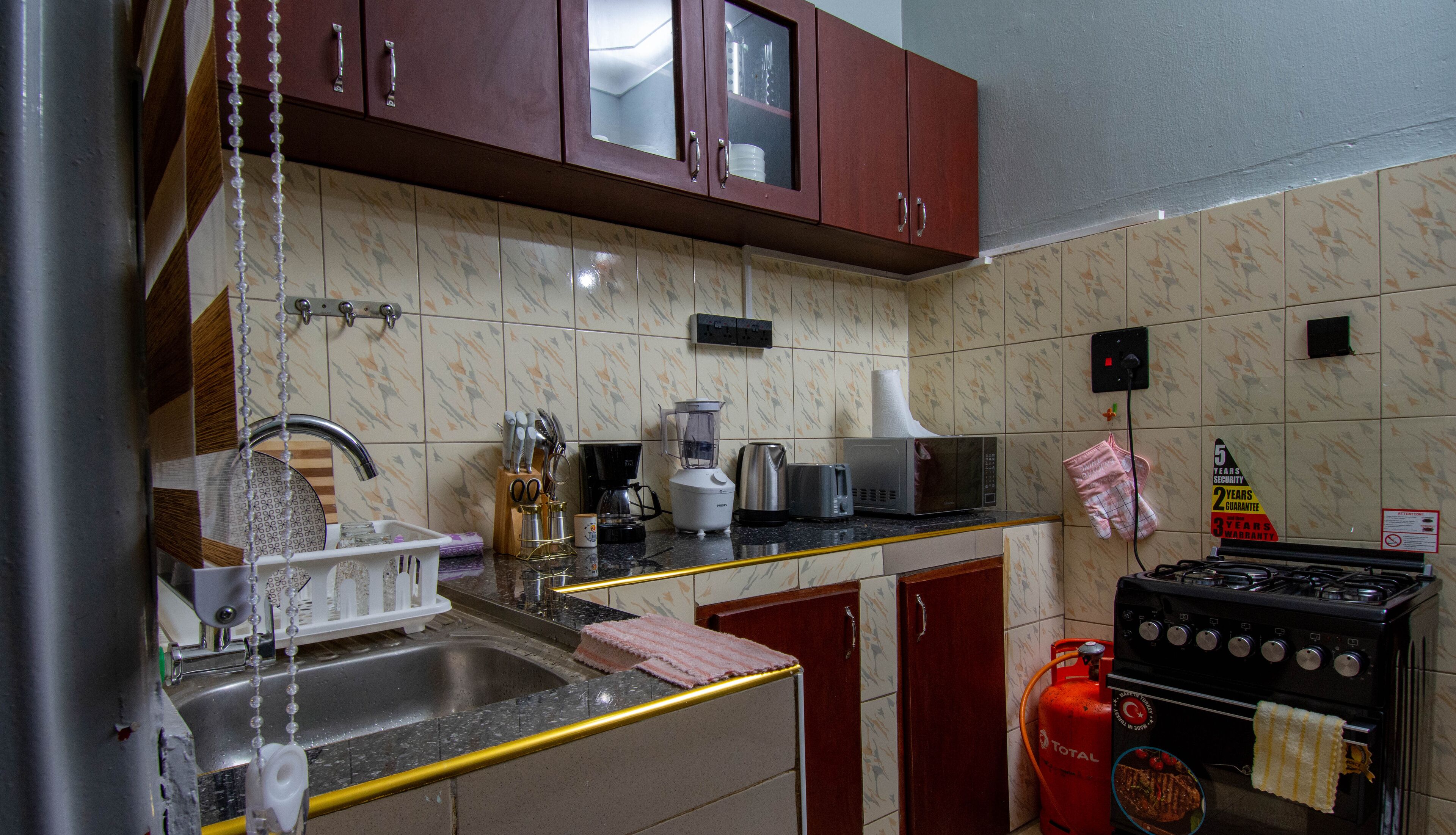 A kitchen with a sink, stove, microwave, and various utensils.