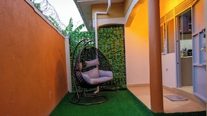 A corner with a hanging chair, a green wall, and a door leading to a room. - Urban Oasis (Kampala)