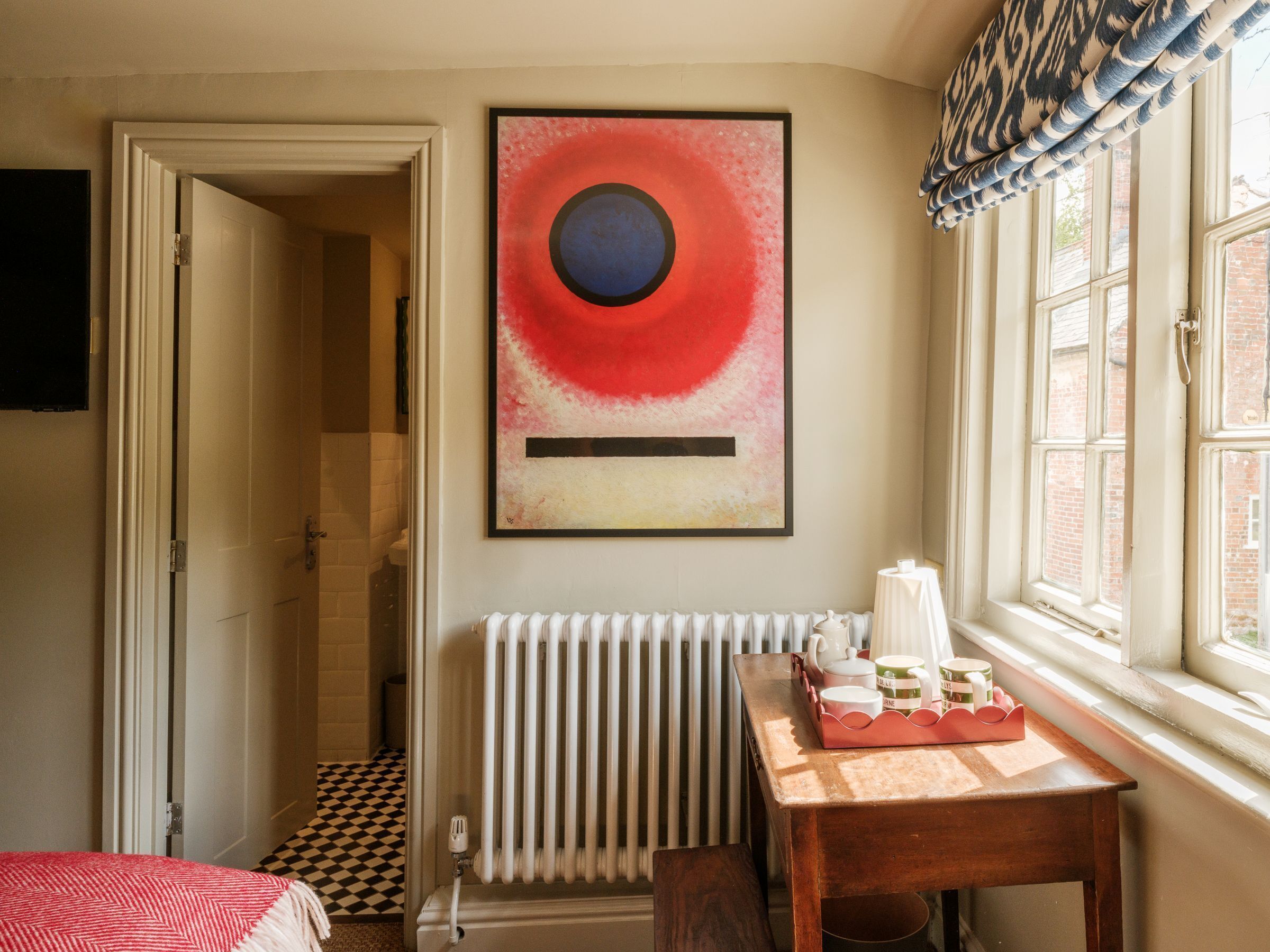Un baño con radiador, una mesa con juego de té y un cuadro en la pared.