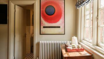 Un baño con radiador, una mesa con juego de té y un cuadro en la pared.