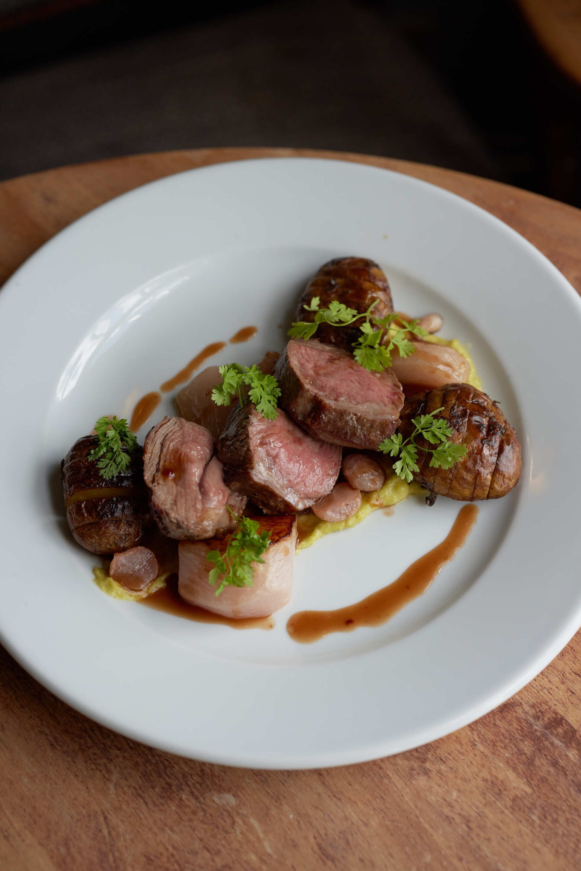 A white plate with sliced meat, garnished with parsley, and a brown sauce.