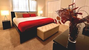 Ein Hotelzimmer mit Bett, Nachttischen, einer Blumenvase und einer Tür.