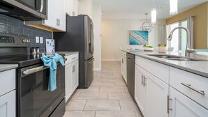A modern kitchen with a black oven, stainless steel appliances, white cabinets, and a tiled backsplash. - 4‑Bed Oasis with Pool at Storey Lake (Kissimmee)
