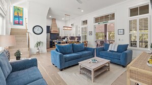 A spacious living room with a blue sofa set, a wooden coffee table, and a kitchen in the background. - Bikes, Private Pool, Putting Green, Close to Seaside and Beach (Santa Rosa Beach)