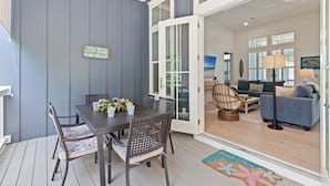 A dining area with a table and chairs, a view of the living room through glass doors, and a beach-themed rug. - Bikes, Private Pool, Putting Green, Close to Seaside and Beach (Santa Rosa Beach)