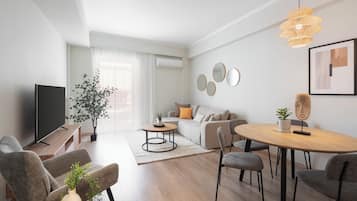 Apartamento superior, 2 quartos, sacada, vista para a cidade | Área de estar | TV 50 polegadas com canais a cabo