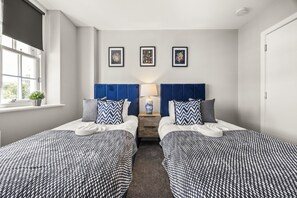 A hotel room with two beds, a window with a view, and three framed pictures on the wall. - Buzzing Brighton Apartments | By My Getaways (Brighton)