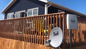 Ein Haus mit einer Holzdachterrasse, einer Satellitenschüssel und einem Schild für Bell Internet.