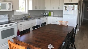 Eine moderne Küche mit weißen Schränken, einem Holzespeisetisch und einer eingebauten Mikrowelle.
