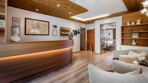 A reception area with a wooden reception desk, framed certificates, a map, and a modern chandelier.