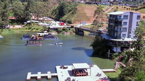 A riverside dock with boats, a covered seating area, and a building with balconies. - Hotel Nova El Peñol (El Peñol)