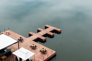 A dock with tables and chairs, a covered seating area, and a building with a metal roof.