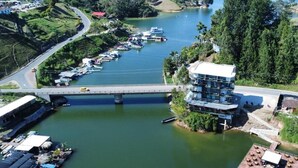 A riverside hotel with a bridge, docked boats, and lush greenery. - Hotel Nova El Peñol (El Peñol)